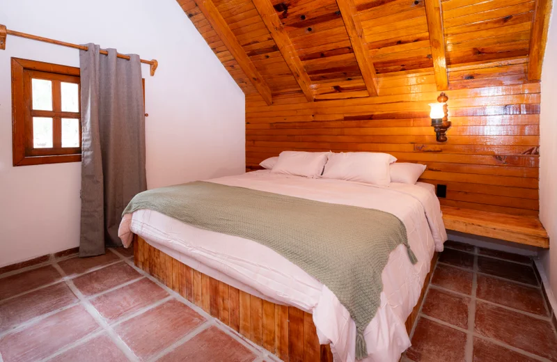 Recámara 1 con cama king size y techo de madera